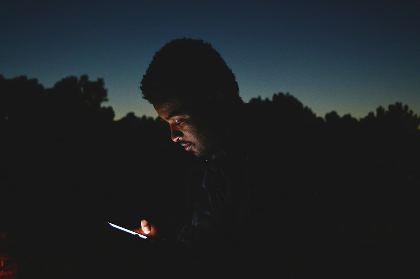 A worker checking their phone at dusk
