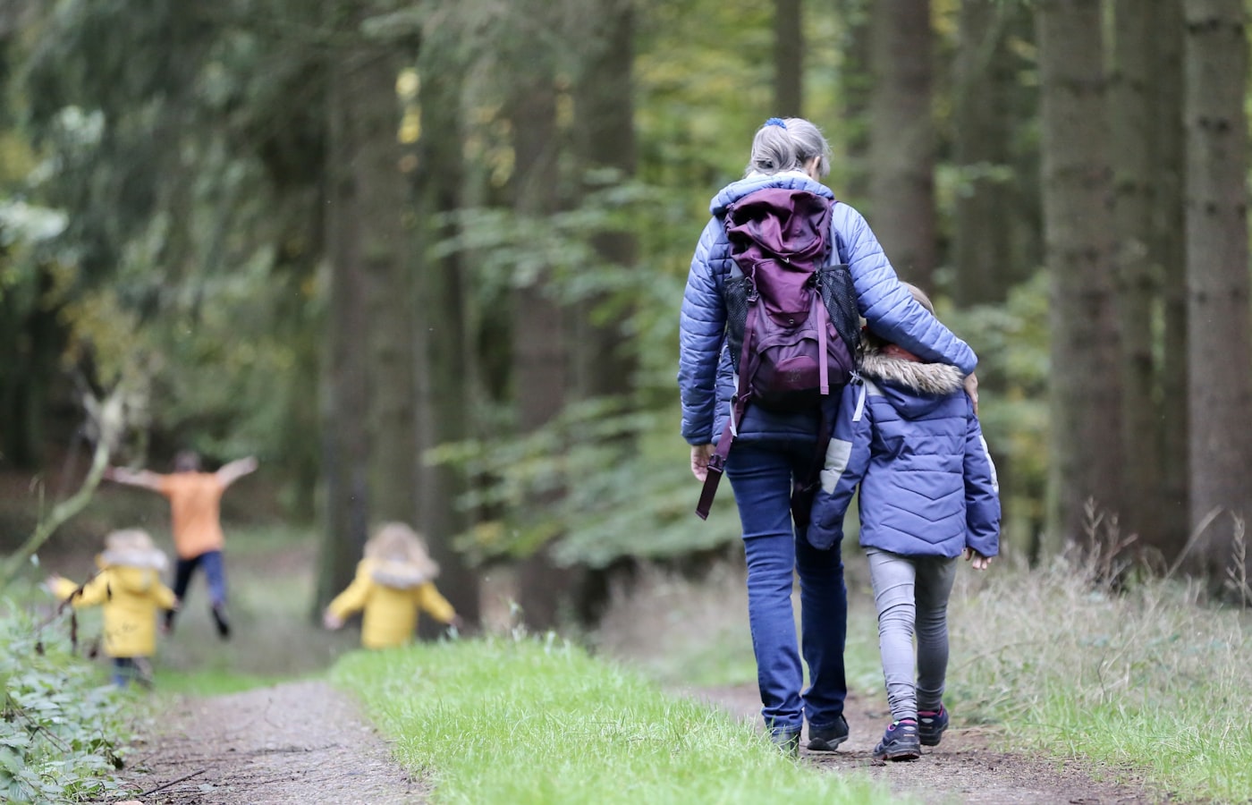 A parent walking through the woods with their children